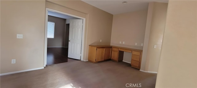 interior space featuring built in desk and dark colored carpet