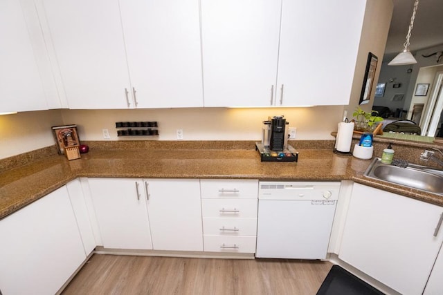 kitchen with sink, white dishwasher, light hardwood / wood-style flooring, white cabinets, and dark stone counters