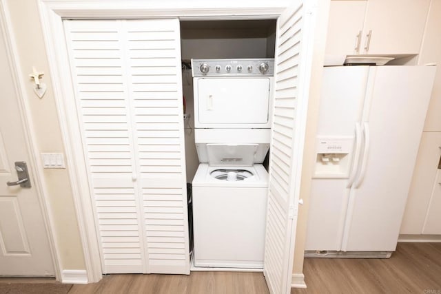 laundry area with stacked washer and dryer and light wood-type flooring