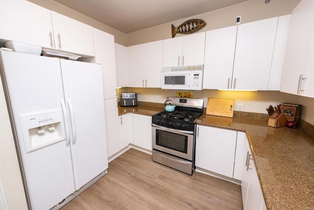 kitchen with white cabinetry, dark stone counters, white appliances, and light hardwood / wood-style floors