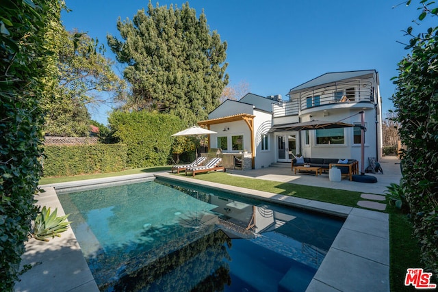 back of house featuring a balcony, a patio area, and outdoor lounge area