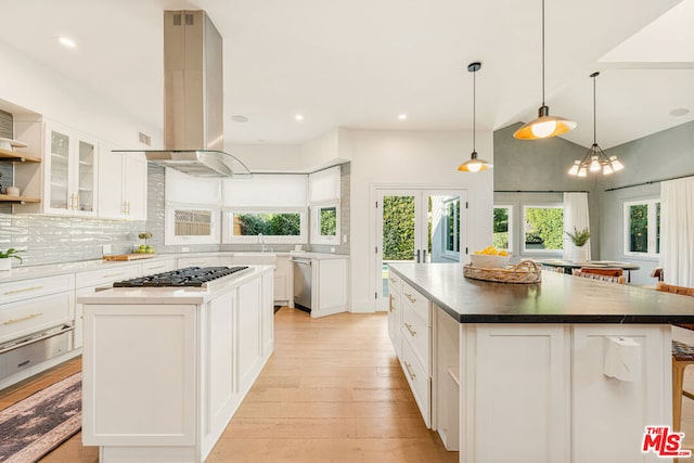 kitchen with appliances with stainless steel finishes, a kitchen island, island range hood, and white cabinetry