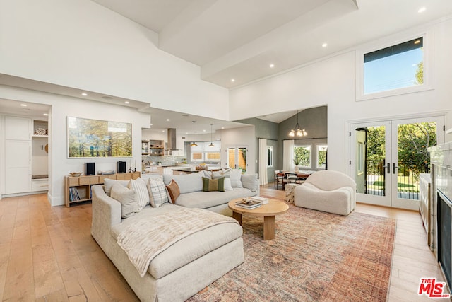 living room featuring a notable chandelier, light hardwood / wood-style flooring, french doors, and high vaulted ceiling