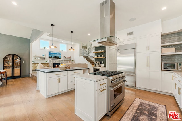 kitchen featuring a center island, white cabinetry, high end appliances, hanging light fixtures, and island range hood