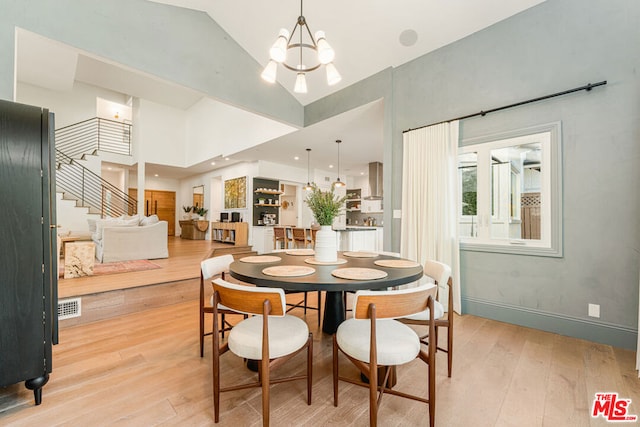 dining space featuring high vaulted ceiling, an inviting chandelier, and light hardwood / wood-style floors