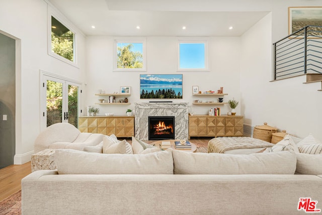 living room featuring a high ceiling, a premium fireplace, and hardwood / wood-style floors