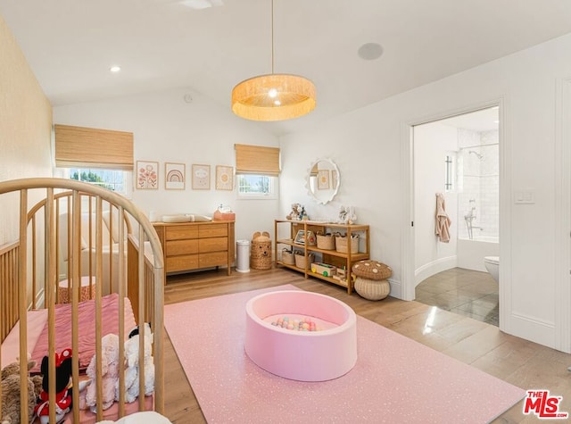 bedroom featuring wood-type flooring, ensuite bath, and vaulted ceiling