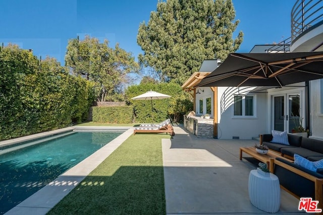 view of swimming pool with a patio area, exterior kitchen, french doors, and outdoor lounge area