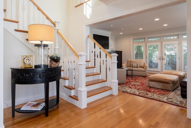 stairs with hardwood / wood-style floors, ornamental molding, and french doors