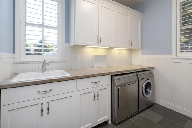 clothes washing area featuring cabinets, washing machine and dryer, sink, and dark tile patterned flooring