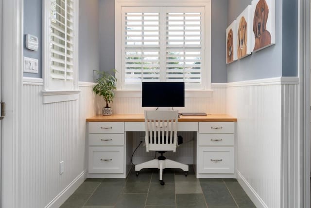 office with built in desk and dark tile patterned floors