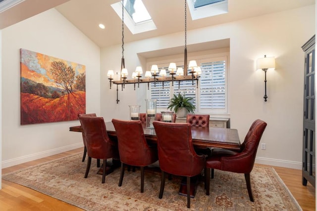 dining area with vaulted ceiling, hardwood / wood-style floors, and an inviting chandelier