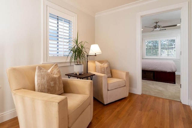 sitting room with ornamental molding, ceiling fan, and light wood-type flooring