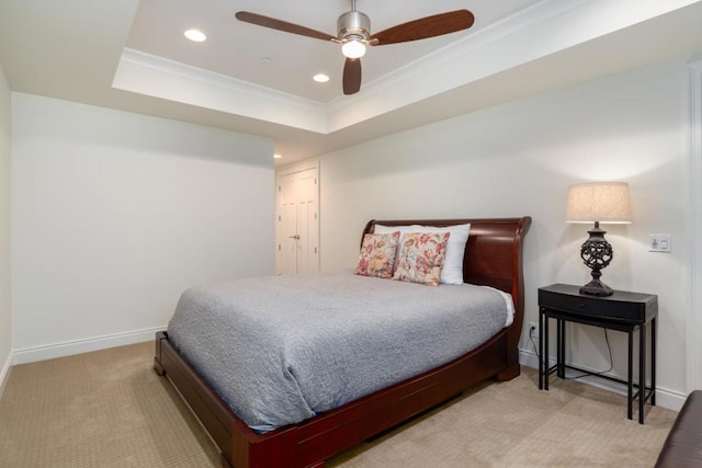 bedroom featuring a raised ceiling, ornamental molding, light colored carpet, and ceiling fan