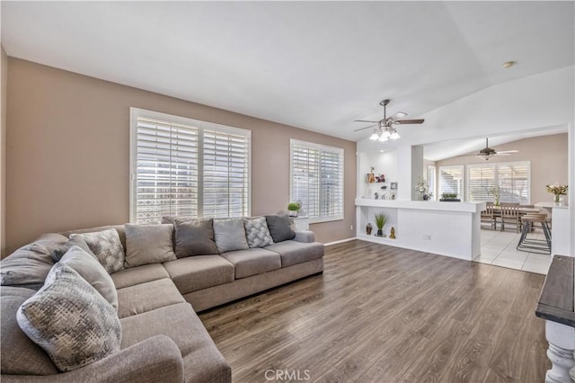 living room with ceiling fan, light wood-type flooring, and vaulted ceiling