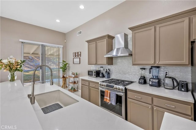 kitchen featuring appliances with stainless steel finishes, sink, backsplash, and wall chimney range hood