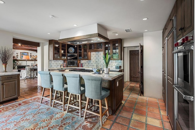 kitchen featuring tasteful backsplash, a center island, double oven, and dark brown cabinets