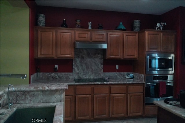 kitchen with light tile patterned floors, stainless steel appliances, light stone counters, and sink