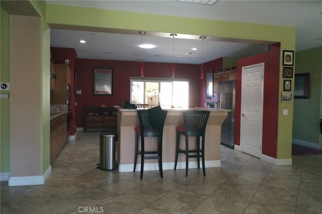 kitchen with kitchen peninsula, stainless steel fridge with ice dispenser, a breakfast bar, a center island, and pendant lighting