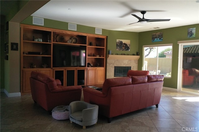 living room featuring ceiling fan, a premium fireplace, and tile patterned flooring