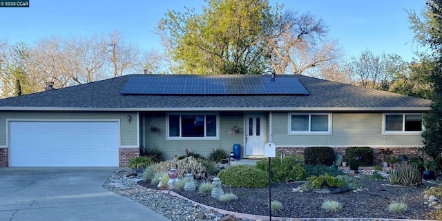 ranch-style house with a garage and solar panels