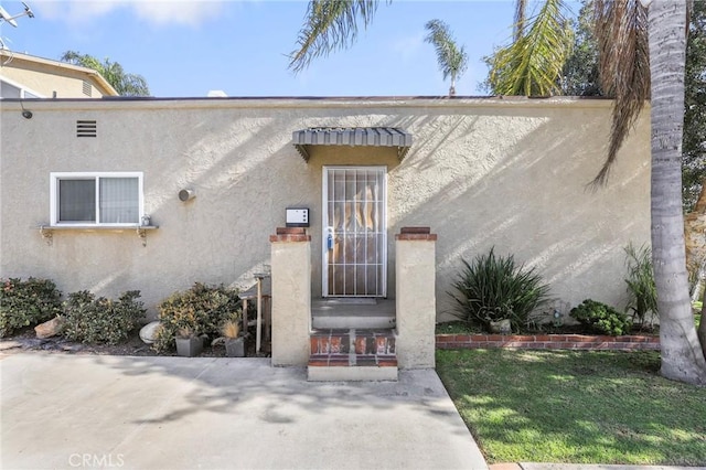 doorway to property featuring a lawn and a patio