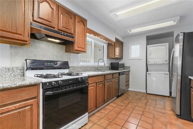 kitchen featuring stainless steel appliances, decorative backsplash, sink, stacked washing maching and dryer, and light tile patterned flooring