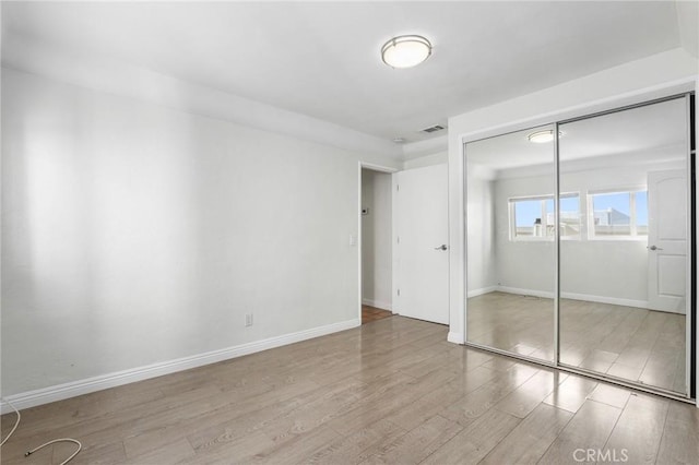 unfurnished bedroom featuring light wood-type flooring and a closet