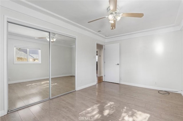 unfurnished bedroom featuring ceiling fan, a closet, crown molding, and light hardwood / wood-style floors