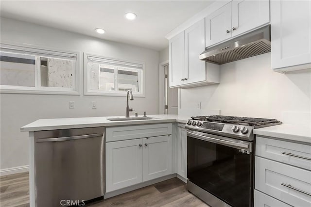 kitchen featuring white cabinetry, light hardwood / wood-style floors, kitchen peninsula, stainless steel appliances, and sink