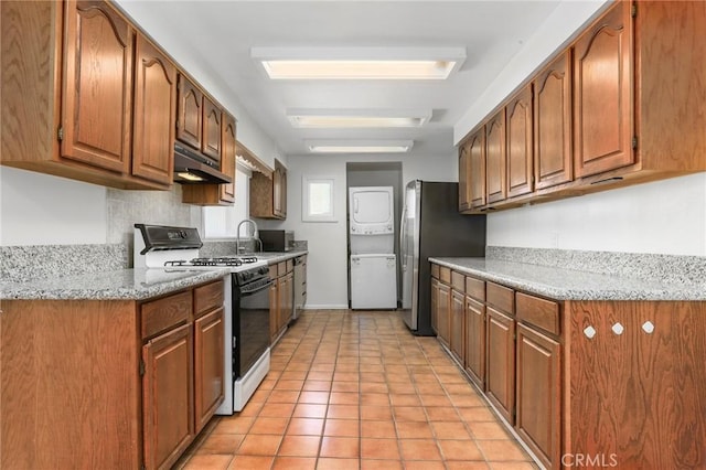 kitchen with light stone counters, light tile patterned floors, stainless steel fridge, and white gas range