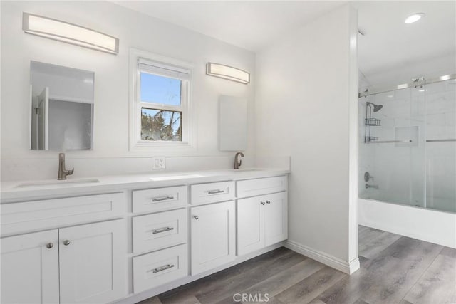 bathroom with bath / shower combo with glass door, wood-type flooring, and vanity