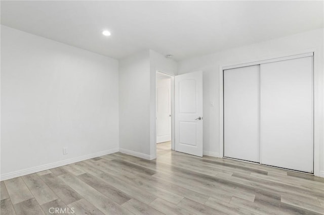 unfurnished bedroom featuring light wood-type flooring and a closet