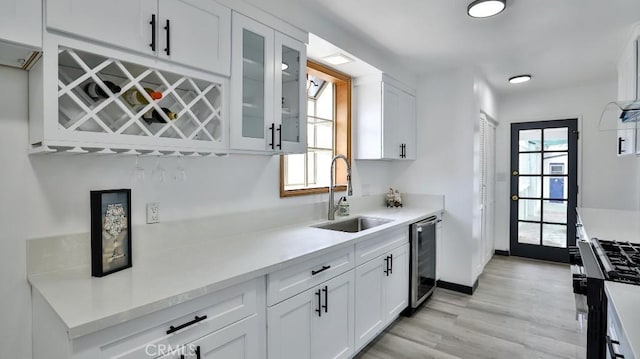 kitchen with a sink, light countertops, glass insert cabinets, white cabinetry, and stainless steel gas stove