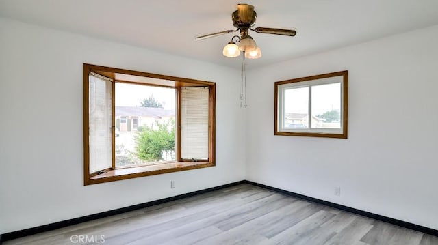 empty room with a ceiling fan, baseboards, a wealth of natural light, and light wood-type flooring