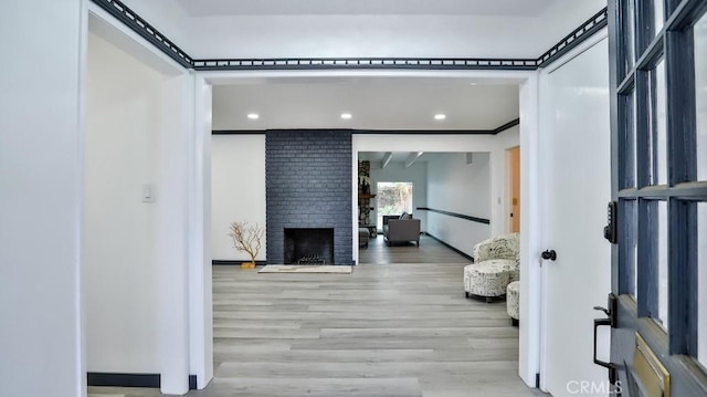 interior space with recessed lighting, a brick fireplace, wood finished floors, and ornamental molding