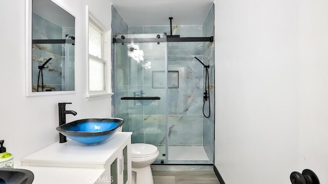 full bathroom with a stall shower, toilet, vanity, and wood finished floors