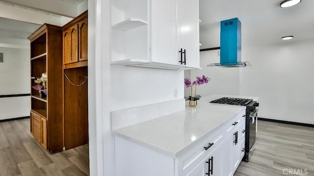 kitchen featuring gas stove, open shelves, light wood-style floors, and extractor fan