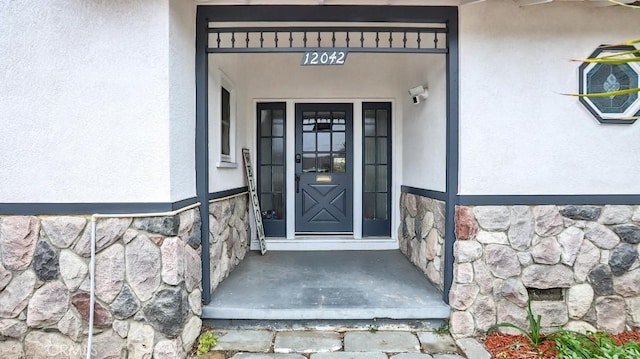 property entrance with stone siding and stucco siding