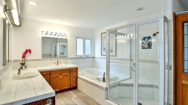 full bath featuring a bath, a shower stall, vanity, and wood finished floors