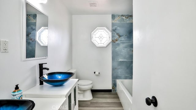 full bath with visible vents, toilet, vanity, and wood finished floors