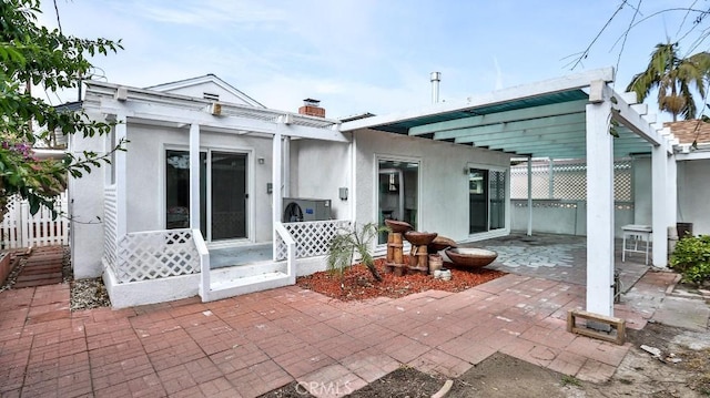 back of house with a patio area, a chimney, stucco siding, and a pergola