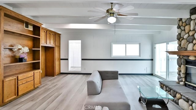 living room with beamed ceiling, visible vents, light wood-style flooring, a stone fireplace, and ceiling fan