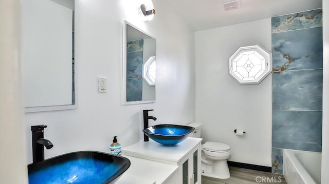 full bathroom with a wealth of natural light, visible vents, a tub, and toilet