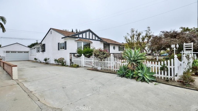 view of front of house featuring a fenced front yard, a detached garage, an outbuilding, and stucco siding