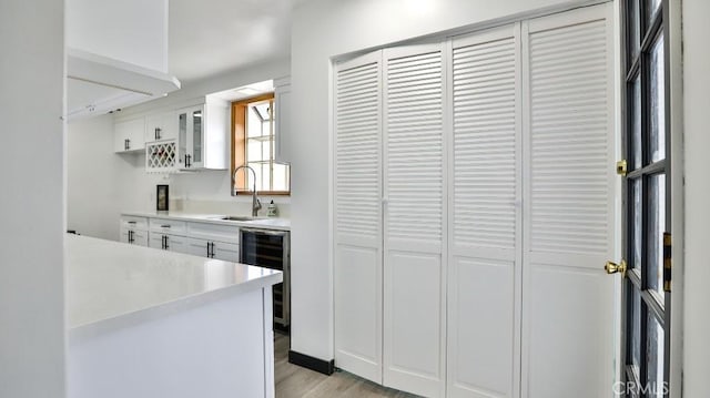 bar featuring light wood-style flooring, beverage cooler, and a sink