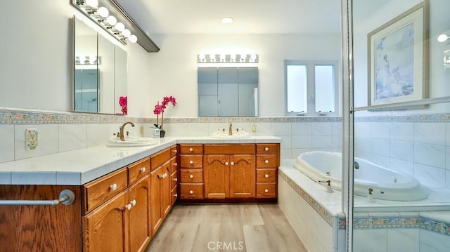 bathroom featuring double vanity, a jetted tub, wood finished floors, and a sink