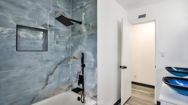 bathroom with visible vents, shower / washtub combination, wood finished floors, and vanity