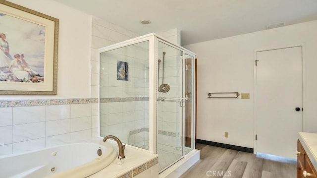 full bathroom with a shower stall, baseboards, a whirlpool tub, wood finished floors, and vanity