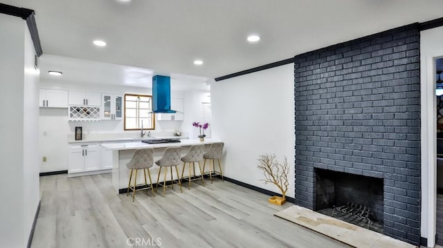 kitchen with white cabinetry, a peninsula, a breakfast bar area, and island exhaust hood